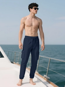 Detail of dark blue men's cargo pants with flap pockets shown on a yacht deck