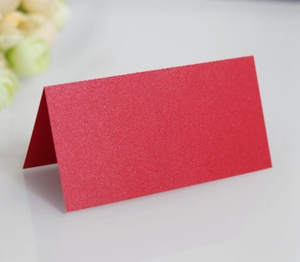 Macro shot of red pearlescent place card with subtle glitter texture on white desk