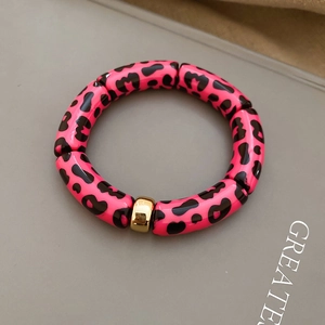 Detailed macro view of leopard print resin beads with a polished gold metallic spacer
