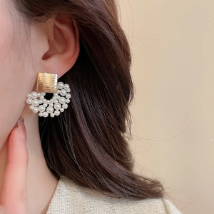 Detailed close-up of French vintage style fan-shaped pearl earrings on model's ear