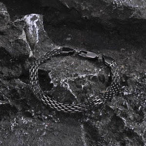 Detail of gunmetal mesh stainless steel bracelet with lobster clasp on dark rock