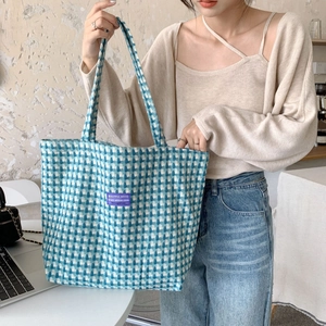 Detailed close-up of blue and white checkered knit tote bag with purple woven label