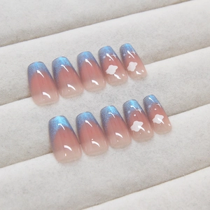 Blue cat-eye press-on nails with white clouds and star patterns on gray velvet box