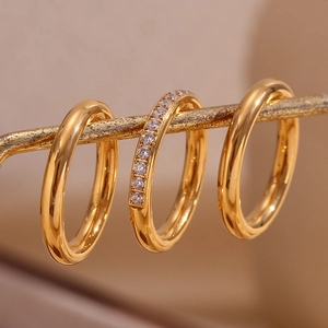 Detail of three 18K gold plated stainless steel rings featuring one zircon paved band