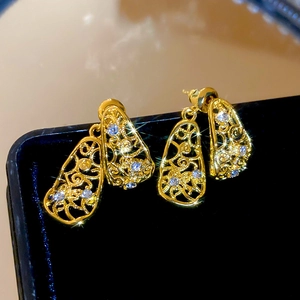Vue détaillée de boucles d'oreilles dorées en forme de larme avec des pierres scintillantes