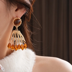Close-up of vintage gold tassel earrings with brown stones and amber beads on model