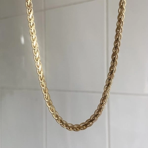 Macro detail of 18k gold plated vintage twisted chain necklace with textured braid