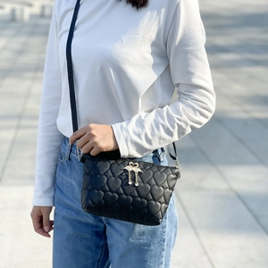 Women's black quilted crossbody bag with golden swan clasp and heart embroidery detail