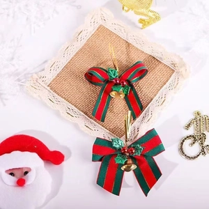 Detail of red and green striped Christmas bows with gold bells and green glitter leaf decor