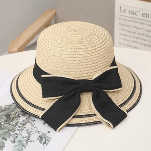 Dettaglio del cappello di paglia beige con un elegante fiocco nero decorativo da donna