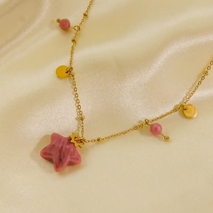 Elegant gold necklace featuring a pink stone star pendant and beads on champagne silk