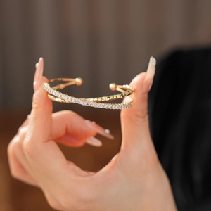 Close-up of golden double-layer cross bracelet with sparkling zircon on model wrist