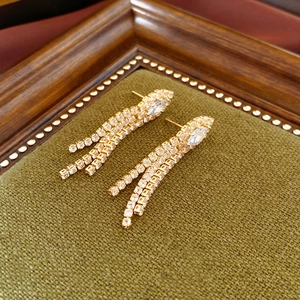 Detailed shot of gold plated tassel earrings with sparkling zircon on a velvet tray