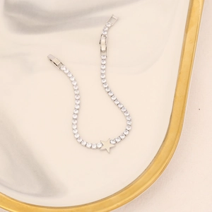 Detail of silver tennis bracelet with star charm and zircons on marble tray