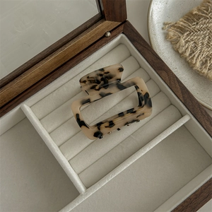 Macro view of a square leopard print acetate hair claw clip in a wooden jewelry box