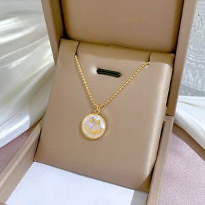 Detailaufnahme einer goldenen Titan-Halskette mit Perlmutt-Smiley in einer Schmuckschatulle