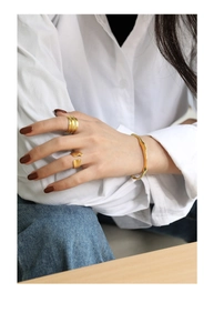 Detailed shot of irregular gold cuff bracelet and matching layered rings on a female model