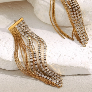 Detailed view of 18K gold plated tassel earrings with zircon chains on a stone base