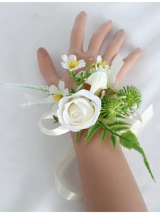 Detail of white artificial rose wrist corsage with silk ribbon for bridesmaids