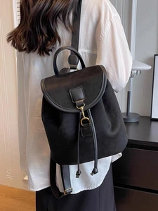 Close-up of black suede backpack featuring leather straps and premium metal hardware details