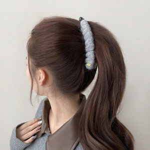 Detailed view of grey knitted acrylic banana hair clip worn on a high ponytail style