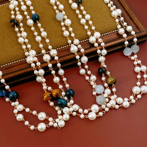 Detailed close-up of multilayer pearl necklace with amber and blue tiger eye stone beads