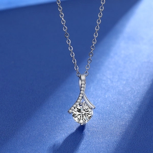 Close-up of a 2ct moissanite pendant with small stones on a silver chain over blue backdrop