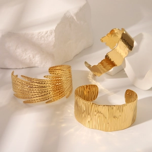 Détails de bracelets ouverts en acier titane doré avec textures de plumes et d'écorce