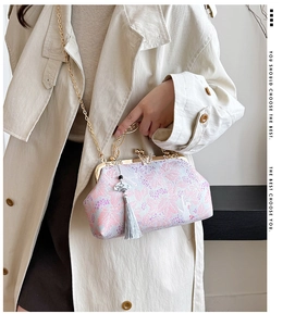 Detailed view of elegant embroidered evening bag featuring tassel charm and gold chain strap