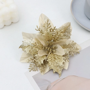 Detailed top view of gold glitter artificial poinsettia flower on white decorative surface