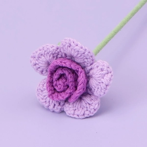 Macro shot of handcrafted crochet purple rose with vibrant petals and green stem