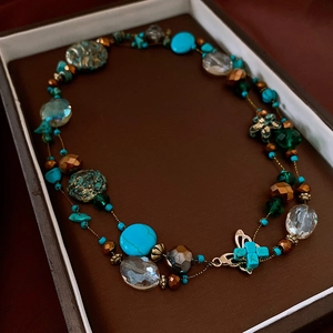 Close-up of retro beaded necklace in turquoise and bronze finish inside a dark gift box