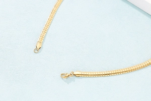 Macro detail of gold stainless steel necklace chain featuring lobster clasp closure