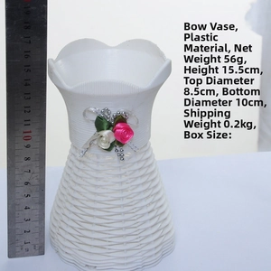 Detail of white textured plastic vase with pink flowers and silver bow, height 15.5cm