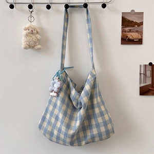 Detail of blue and white checkered canvas tote bag with a cute plush flower pendant