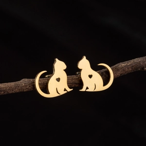 Detailed view of golden cat stud earrings with heart cutout on a natural wooden branch