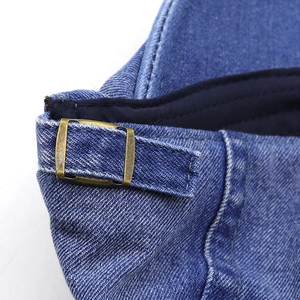 Macro detail of adjustable copper buckle and denim texture on the blue sun hat