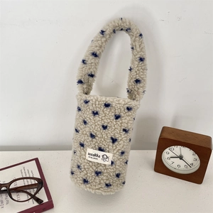 Close-up of plush white drink carrier bag with blue heart patterns and soft wool texture