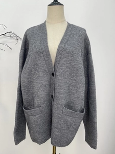 Loose V-neck grey knit cardigan with black buttons and pockets for a vintage winter style