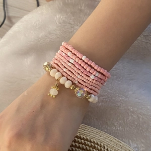 Close-up of bohemian multilayer pink seed bead bracelets with white faux pearls and gold accents
