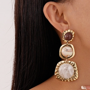 Macro detail of vintage resin earrings with geometric patterns and hammered gold finish