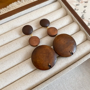 Détail de boucles d'oreilles vintage en perles de bois brun sur plateau en velours