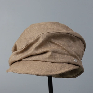 Detail of cotton linen newsboy hat with pleated design and metallic logo accent