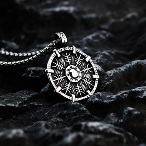 Macro shot of silver Nordic Viking compass pendant on dark rocky texture background