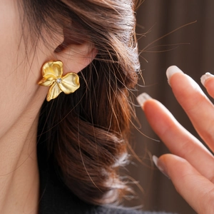 Detail of vintage gold textured bow earrings with central sparkling diamond on model