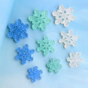 Macro shot of glittery resin snowflake charms in blue and white for DIY craft decoration