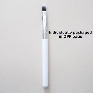 Close-up of a silicone lip brush with a white handle and silver ferrule in opp bag packaging