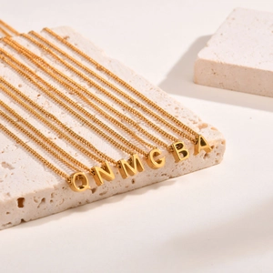 Detailed view of six gold-plated letter pendants on stainless steel cable chains