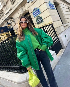 Detail of oversized green winter jacket styled with yellow handbag on a Paris street