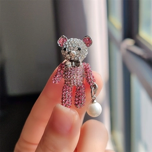 Macro detail of cute bear brooch with pink rhinestones, silver bow and white pearl